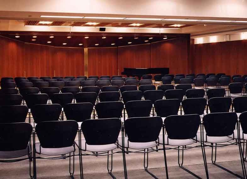 A room with rows of empty chairs facing a stage