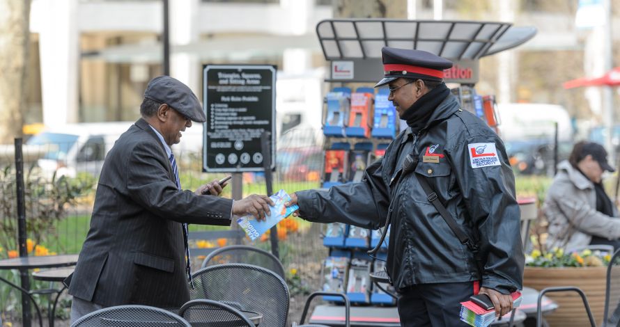 Public Safety Officer hands a pedestrian an area map