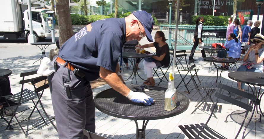 Clean Team Member wipes down an LSBID mesh table in Richard Tucker Park
