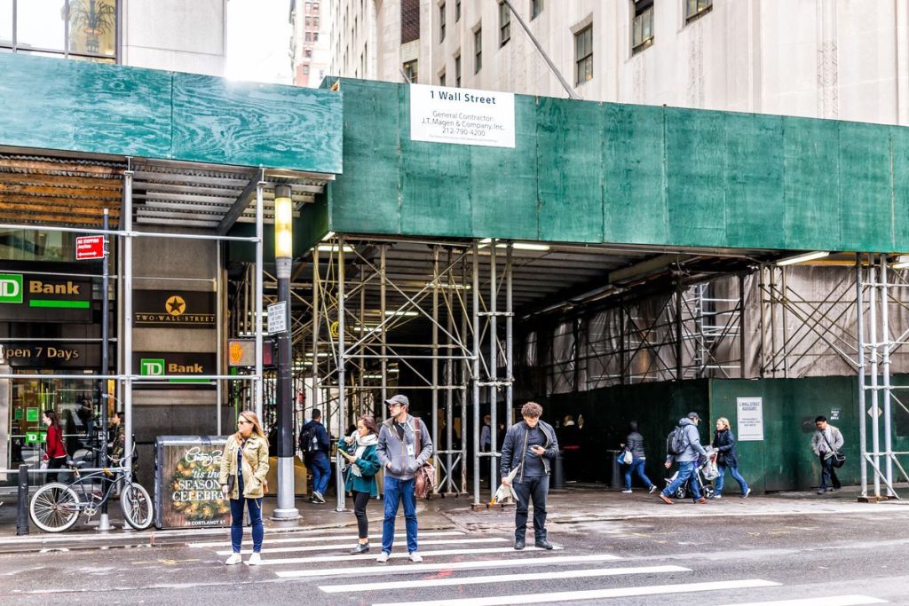 a sidewalk shed stands around a construction site downtown