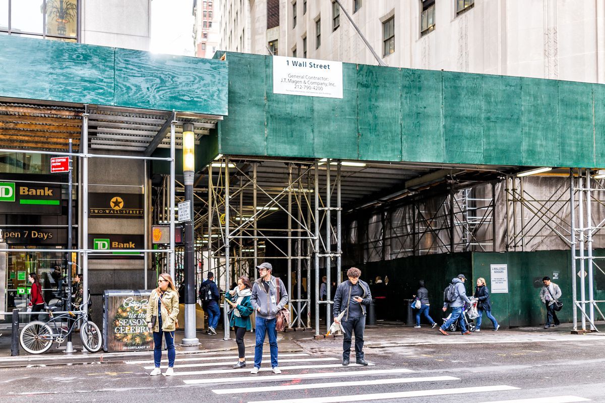 a sidewalk shed stands around a construction site downtown